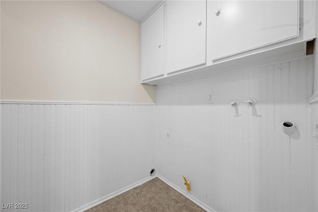 laundry room featuring gas dryer hookup, cabinet space, and wainscoting