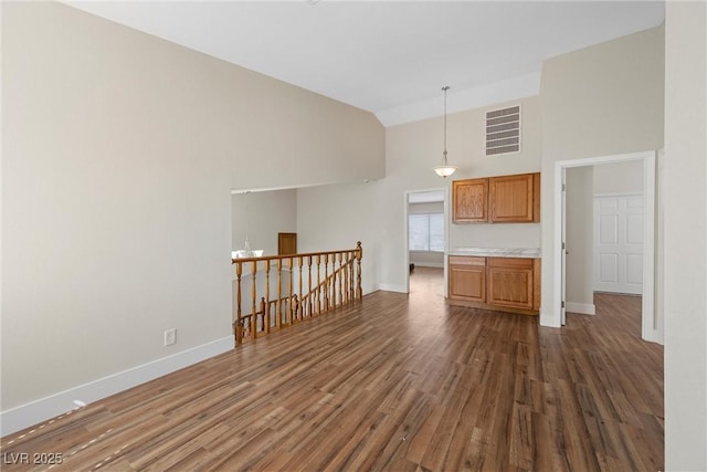 interior space with dark wood-style floors, brown cabinets, visible vents, high vaulted ceiling, and baseboards