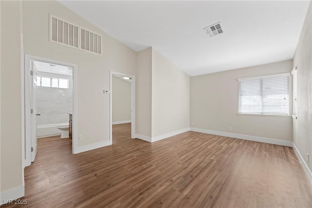 unfurnished room featuring wood finished floors, visible vents, and baseboards