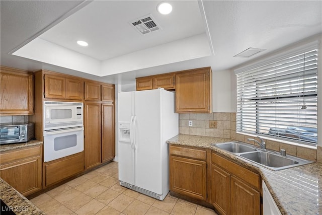 kitchen with a toaster, a raised ceiling, visible vents, a sink, and white appliances