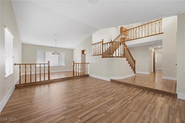 empty room featuring an inviting chandelier, baseboards, visible vents, and wood finished floors