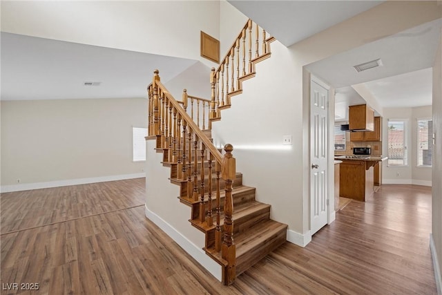 staircase with visible vents, baseboards, and wood finished floors