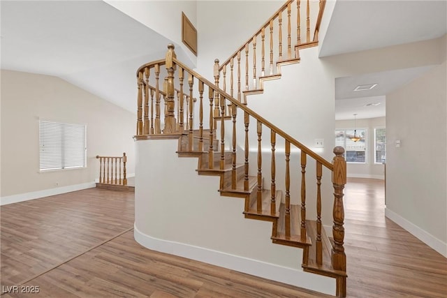 staircase with lofted ceiling, wood finished floors, and baseboards