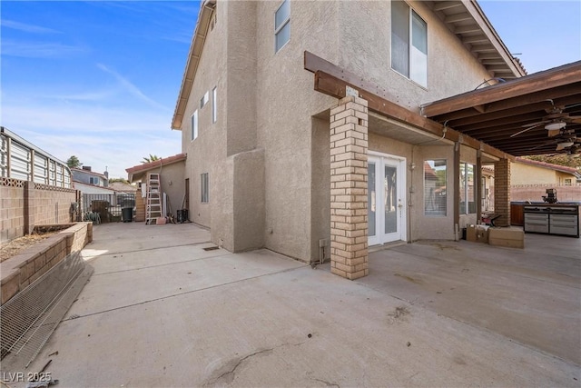 exterior space with french doors, stucco siding, a patio area, ceiling fan, and a fenced backyard