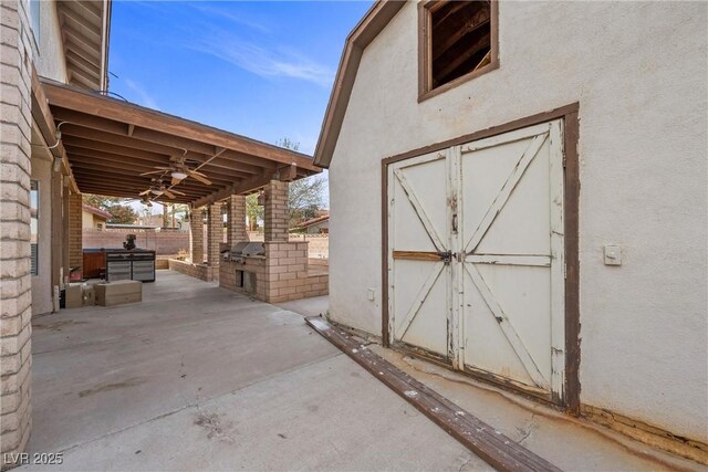 view of outdoor structure with an outdoor kitchen, fence, and an outdoor structure