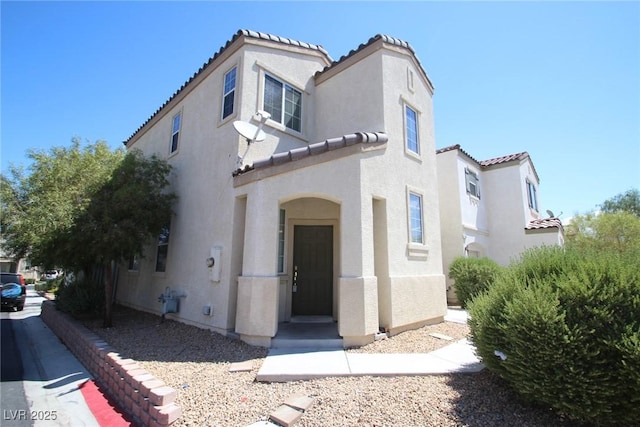 mediterranean / spanish home featuring a tiled roof and stucco siding