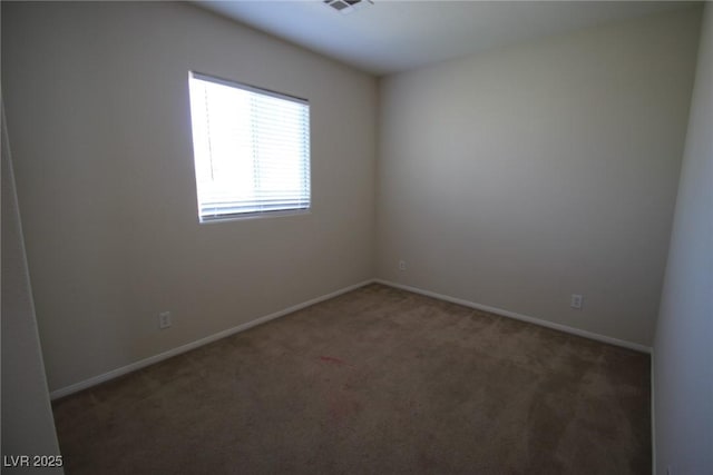 spare room featuring visible vents, baseboards, and dark colored carpet