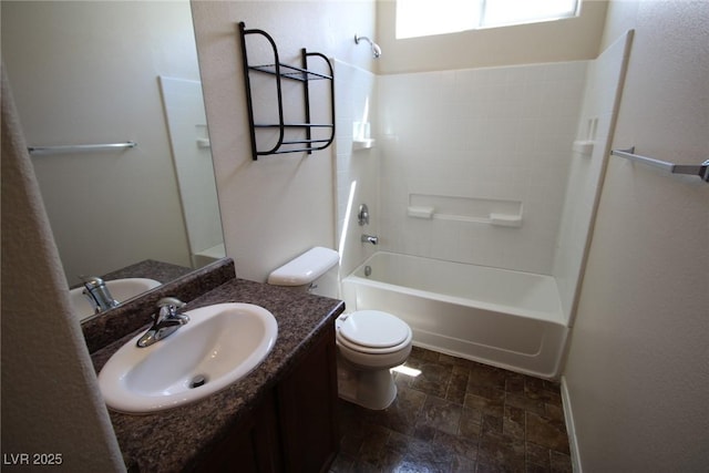 bathroom with stone finish flooring, shower / bath combination, vanity, and toilet