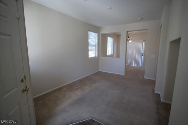 unfurnished room featuring dark carpet and baseboards