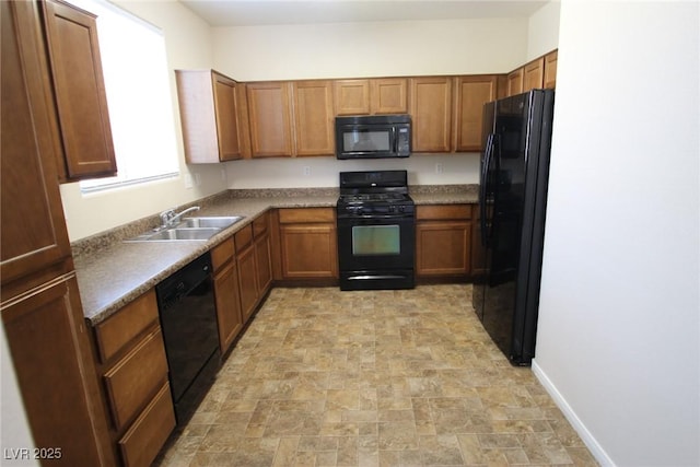 kitchen featuring black appliances, stone finish flooring, and brown cabinets