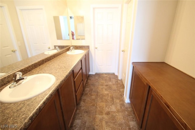 bathroom featuring double vanity, stone finish flooring, and a sink