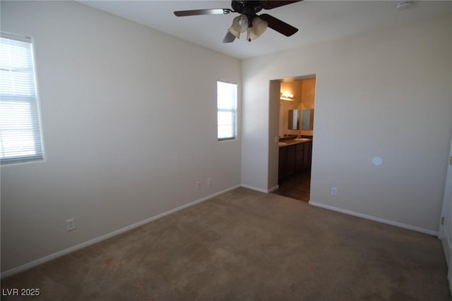 empty room featuring dark carpet, a ceiling fan, and baseboards