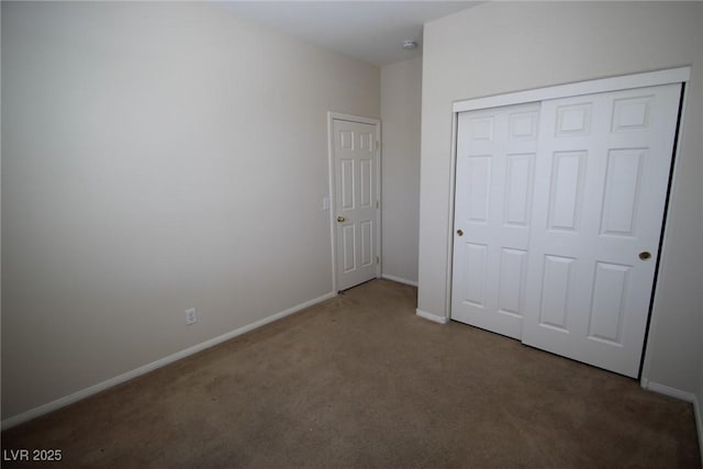 unfurnished bedroom featuring dark colored carpet, a closet, and baseboards