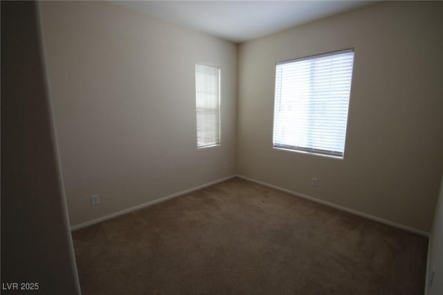 spare room featuring dark carpet and baseboards