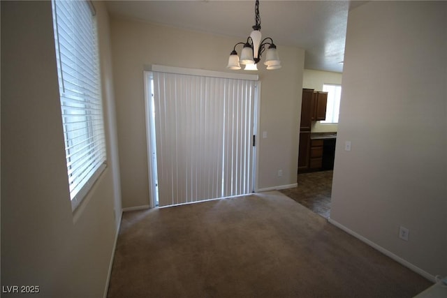 unfurnished dining area with dark colored carpet, baseboards, and an inviting chandelier