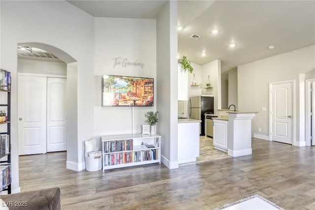 kitchen with arched walkways, light countertops, visible vents, freestanding refrigerator, and white cabinetry