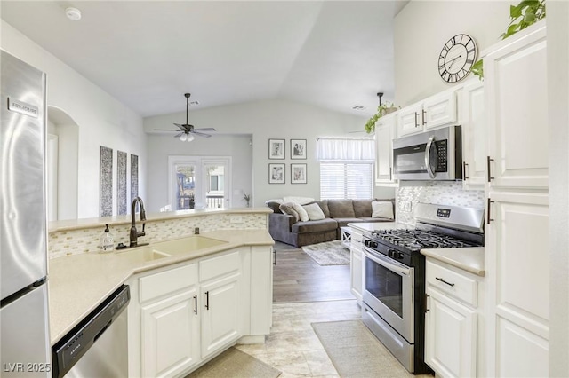 kitchen featuring light countertops, appliances with stainless steel finishes, open floor plan, white cabinetry, and a sink