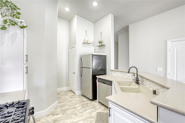 kitchen featuring stainless steel appliances, light countertops, white cabinetry, a sink, and recessed lighting