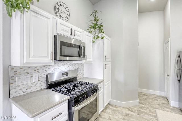 kitchen with appliances with stainless steel finishes, tasteful backsplash, light countertops, and white cabinetry