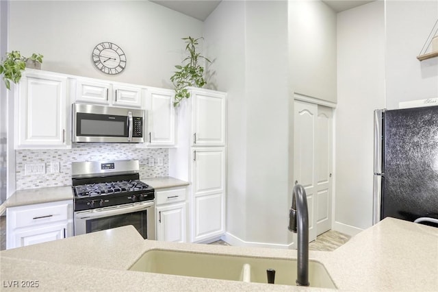 kitchen with white cabinetry, stainless steel appliances, and light countertops