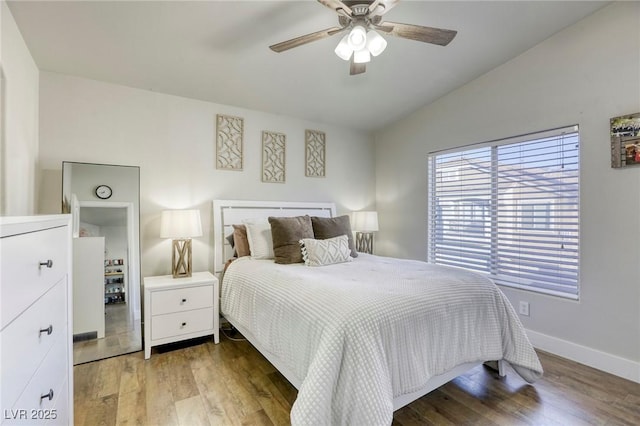 bedroom featuring a ceiling fan, lofted ceiling, baseboards, and wood finished floors