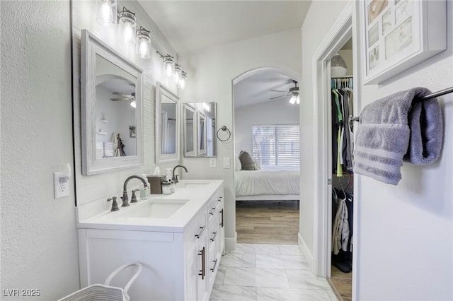 ensuite bathroom with marble finish floor, ceiling fan, and a sink