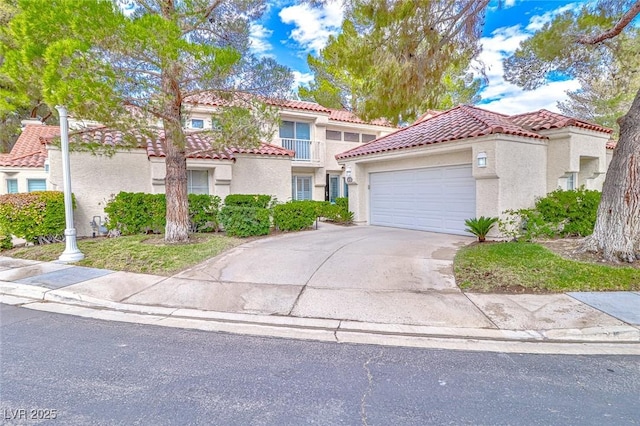 mediterranean / spanish-style house with an attached garage, driveway, a tiled roof, and stucco siding