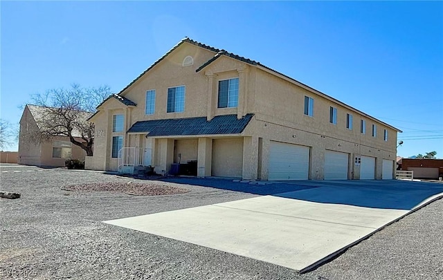 view of front of home featuring driveway, a garage, central AC, and stucco siding