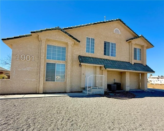 back of property with a tile roof and stucco siding