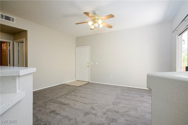 unfurnished room featuring a ceiling fan, carpet, visible vents, and baseboards