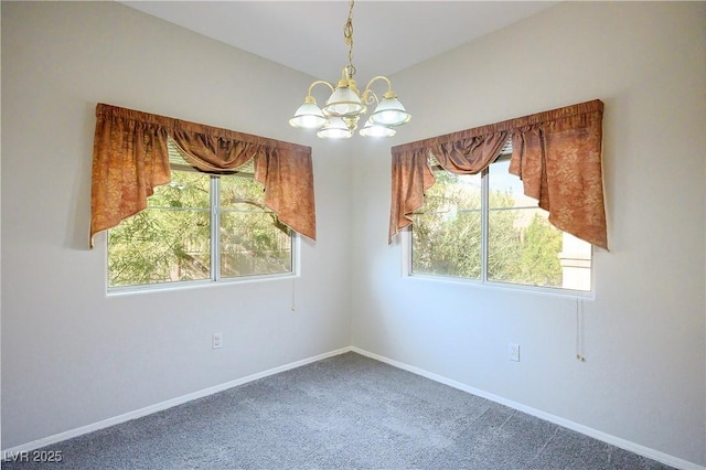 carpeted spare room featuring a chandelier, a healthy amount of sunlight, and baseboards