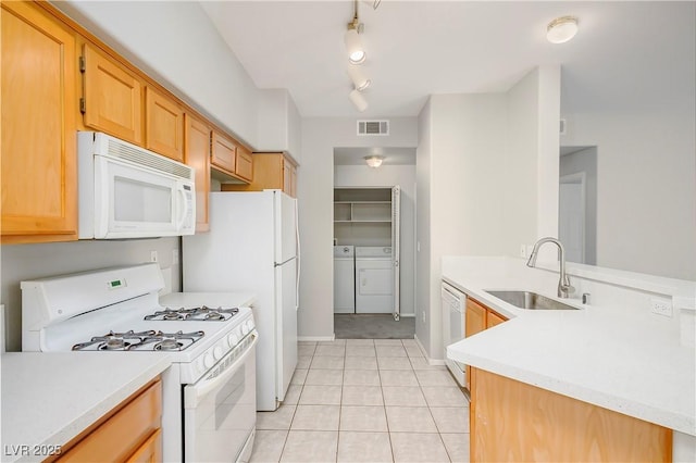 kitchen with light countertops, visible vents, a sink, white appliances, and independent washer and dryer