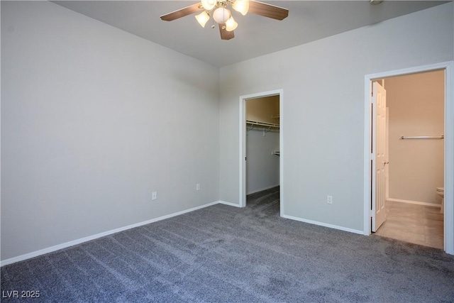 unfurnished bedroom featuring carpet floors, a walk in closet, connected bathroom, and baseboards