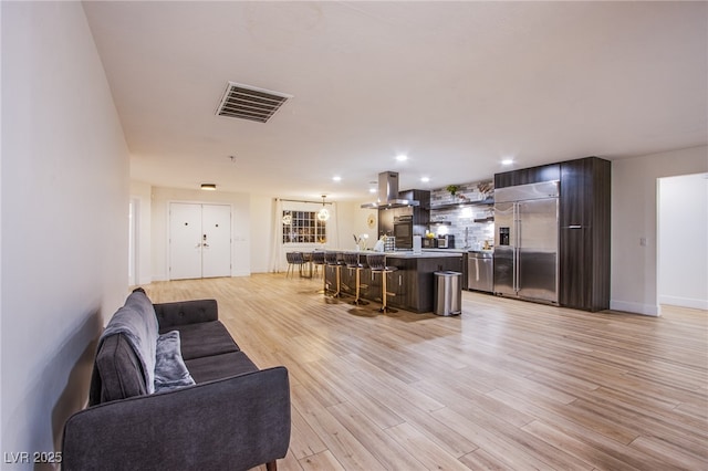 living area with light wood-style floors, baseboards, visible vents, and recessed lighting