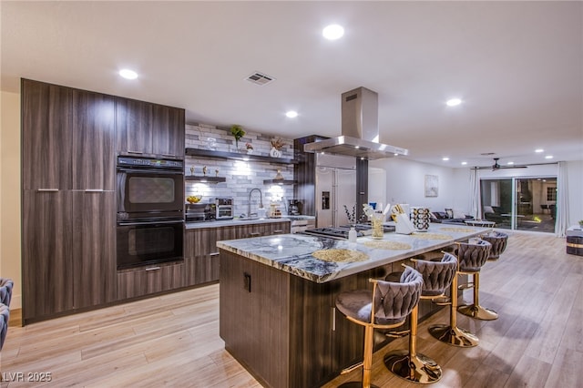 kitchen with appliances with stainless steel finishes, modern cabinets, visible vents, and island range hood