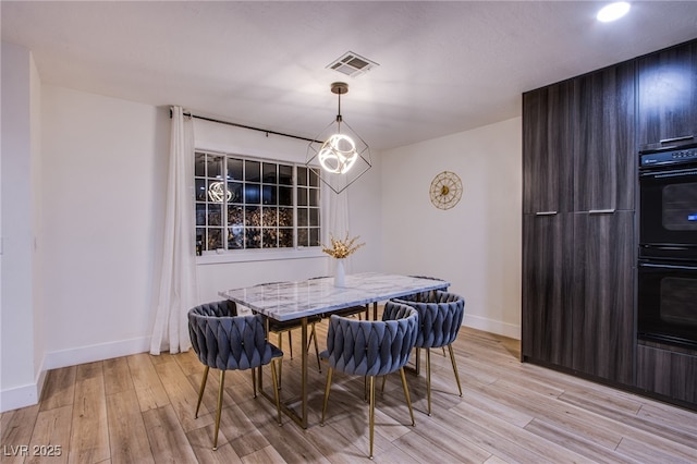 dining area with light wood finished floors, visible vents, and baseboards