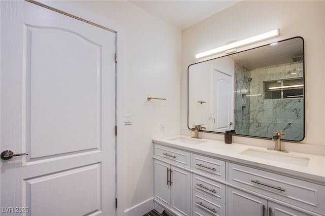 full bathroom with baseboards, a sink, a marble finish shower, and double vanity