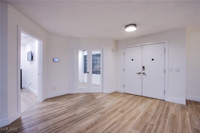 foyer with french doors, baseboards, and light wood finished floors