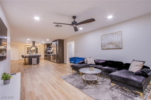 living area featuring a ceiling fan, light wood-type flooring, visible vents, and recessed lighting