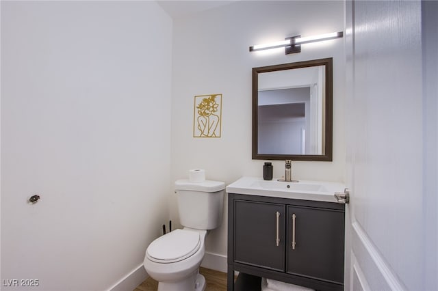 bathroom featuring baseboards, vanity, and toilet