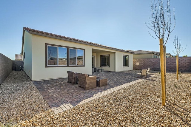 rear view of property with a patio area, a fenced backyard, a tile roof, and stucco siding