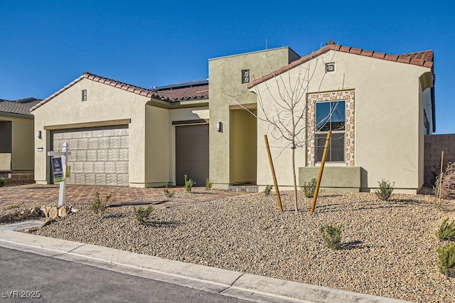 mediterranean / spanish home featuring a garage, a tiled roof, and stucco siding