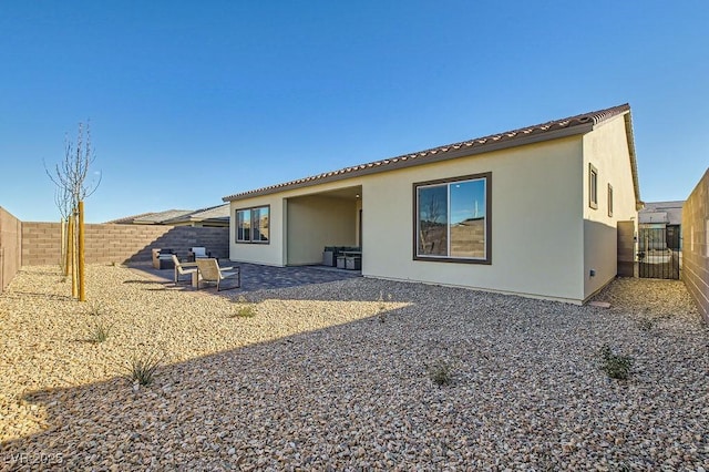 rear view of property featuring a fenced backyard and stucco siding