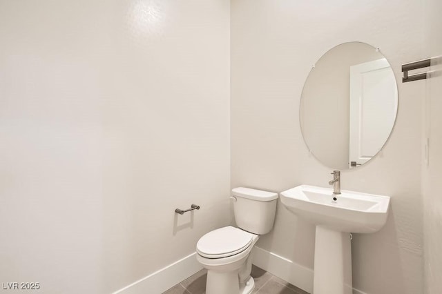 half bathroom featuring baseboards, toilet, and tile patterned floors