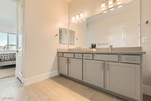 ensuite bathroom with tile patterned flooring, connected bathroom, baseboards, and double vanity