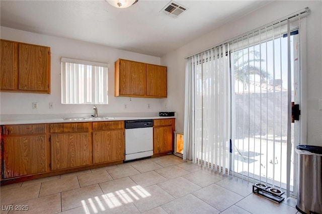 kitchen featuring visible vents, dishwashing machine, brown cabinets, light countertops, and a sink