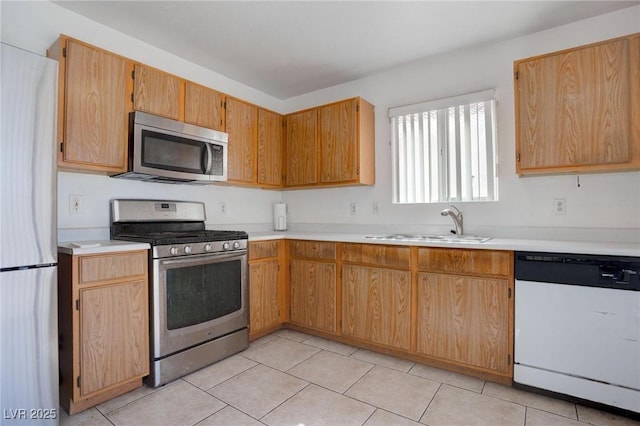 kitchen with a sink, stainless steel appliances, light tile patterned flooring, and light countertops