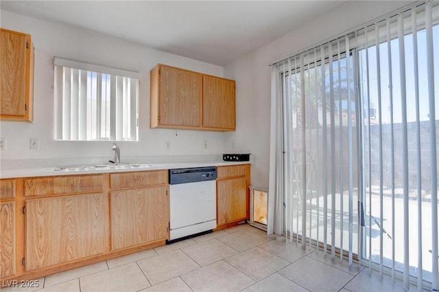 kitchen with light tile patterned floors, light countertops, light brown cabinetry, white dishwasher, and a sink