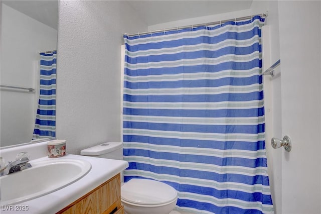 bathroom with curtained shower, a textured wall, vanity, and toilet