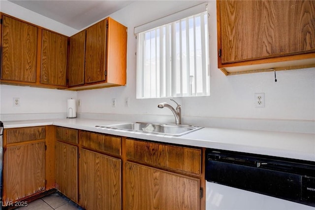 kitchen featuring light countertops, brown cabinetry, light tile patterned flooring, a sink, and dishwasher